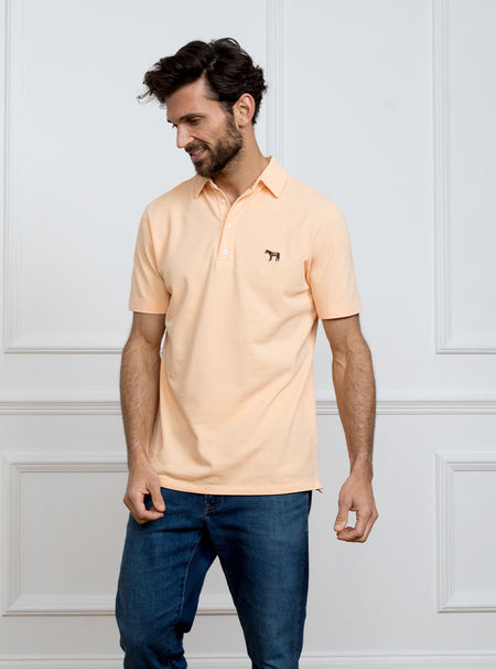 Man wearing peach coloured polo shirt in 100% cotton with Newmarket 875 horse logo embroidered on the front.